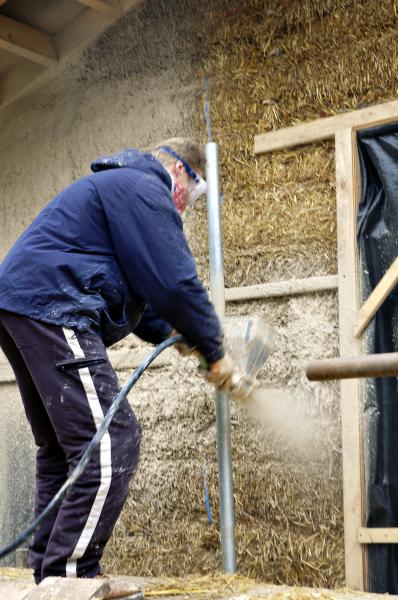 Lime render being sprayed on a straw bale wall.