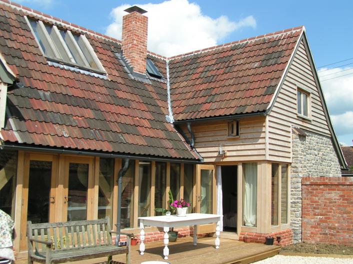 The outside of an oak framed house made using reclaimed stone and tiles.